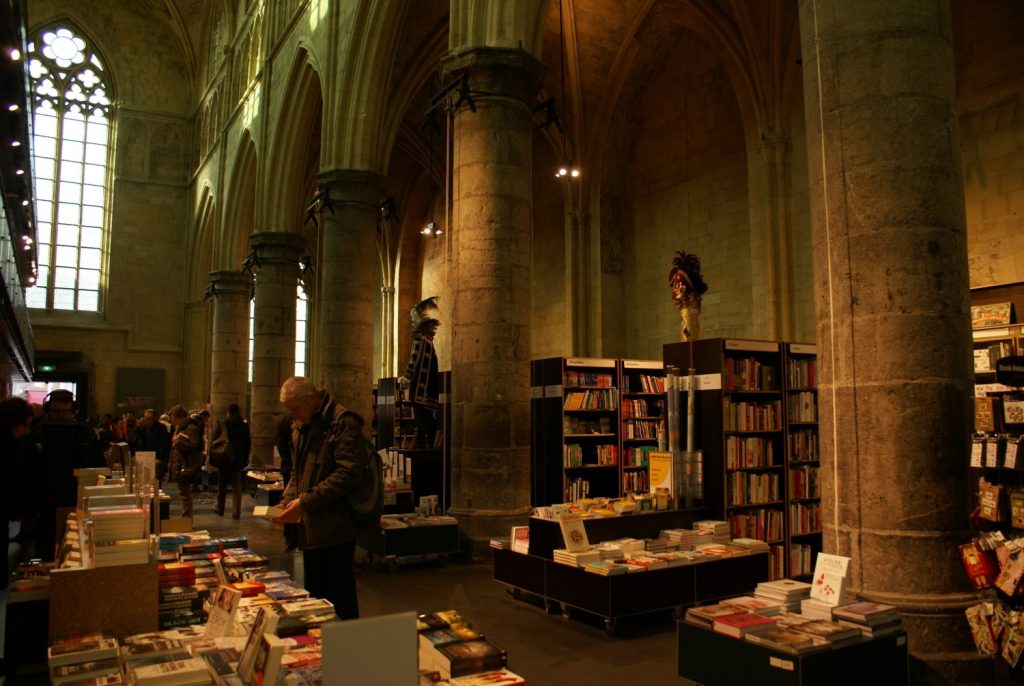 A picture of a bookstore situated in the interior of an old gothic church. This illustrates broad attention while waiting in the bookstore.